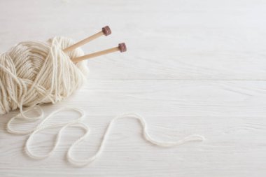 Sıcak, sade bir ortam. Kadın örgü hobisi. Sıcak renklerde iplik. Pembe, şeftali, bej, beyaz ve yeşil. Bir kadın süveteri örme sürecinin başlangıcı.