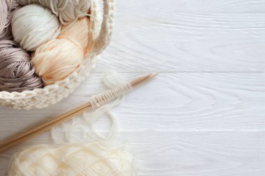 Sıcak, sade bir ortam. Kadın örgü hobisi. Sıcak renklerde iplik. Pembe, şeftali, bej, beyaz ve yeşil. Bir kadın süveteri örme sürecinin başlangıcı.