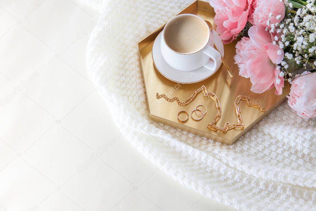 Breakfast for the woman in bed. Coffee in a white mug. Nordic style. White knitted plaid. Bouquet of flowers.