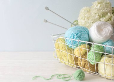 Duvarda puantiyeli duvar kağıdı var. Sepetin içindeki dikiş işi masanın üstünde. Uzayı kopyala Kadın hobisi..