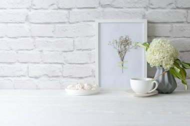 Eski beyaz tuğlalardan bir duvar. İskandinav tarzında gri vazo. Bir buket beyaz ortanca..