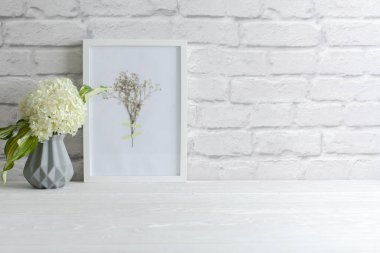 Eski beyaz tuğlalardan bir duvar. İskandinav tarzında gri vazo. Bir buket beyaz ortanca..
