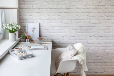 Pencerenin yanında beyaz ve altın kırtasiyeli bir kadın işyeri. Battaniye ve yastıklı beyaz sandalye. Hafif halı. Vazoda çiçekler ve masanın üstünde süslemeler. Çay ve bizet bir tepside.