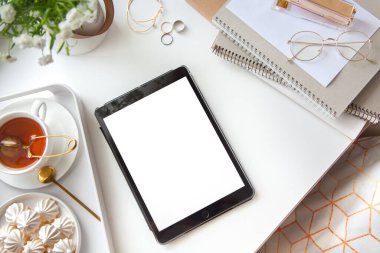 Kadın işyerindeki beyaz ve altın kırtasiyesi. Mücevher, bilezik ve yüzükler. Vazoda çiçekler, çay ve bizet. Çalar saat ve domuz kumbarası. İskandinav İskandinav tarzı.