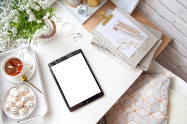 Kadın işyerindeki beyaz ve altın kırtasiyesi. Mücevher, bilezik ve yüzükler. Vazoda çiçekler, çay ve bizet. Çalar saat ve domuz kumbarası. İskandinav İskandinav tarzı. Tarz sahibi kadınlar masası, ofis masası..