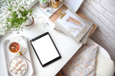 Kadın işyerindeki beyaz ve altın kırtasiyesi. Mücevher, bilezik ve yüzükler. Vazoda çiçekler, çay ve bizet. Çalar saat ve domuz kumbarası. İskandinav İskandinav tarzı.