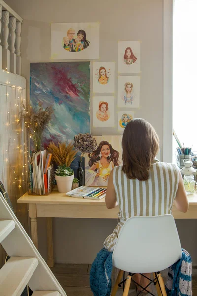 소녀는 직장에 앉아서 초상화를 물감으로 그리고 작품들은 고양이를 페인트 꽃들이 — 스톡 사진