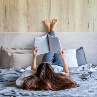 Kitap ya da gazete okuyan ve sabahları yatakta kahve içen bir kadın. Kız baş aşağı yatıyor..