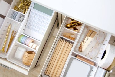 Female workplace. White work table. The stylish gold stationery is arranged very neatly in the drawers of the desk. Japanese storage method. clipart