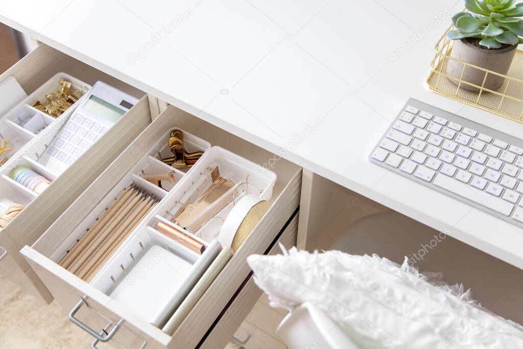 Female workplace. White work table. The stylish gold stationery is arranged very neatly in the drawers of the desk. Japanese storage method.