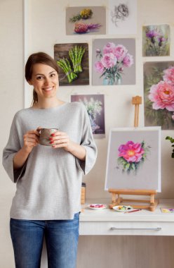 Hoş, genç, çıplak ayaklı bir sanatçı, sehpanın üzerinde duran parlak pembe bir gül kalçası ve aletlerin taslağını yazdıktan sonra rahatlarken kahve içer.