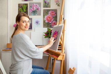 Genç kadın ressamın arka görüntüsü, açık hava ahşap bir sehpada otururken atölyesinde kuru pastel boya kalemleri olan bir kutudan pembe şakayık resmi çiziyor. Yaratıcılık ve hobi konsepti. Pembe gölgeler.