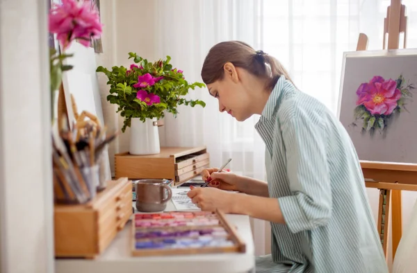 예술가의 모습은 직장에서 장미와 분홍색 조랑말로 부케를 그린다 그녀의 책상에는 — 스톡 사진
