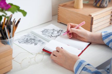 Üst düzey bir sanatçı, iş yerinde çiçek buketleri ve yaratıcılık için malzemelerle oturan gül kalçası çiçekleri çizer. Hobi ve yaratım konsepti