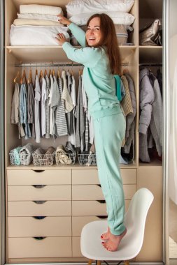 Genç bir kadının gardırobu. Depo ve sipariş üst raftaki dolapta. Bavul ve yatak.