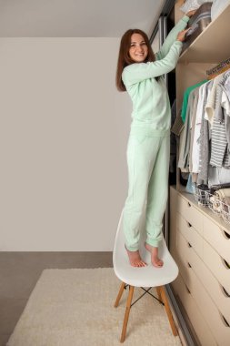 Genç bir kadının gardırobu. Depo ve sipariş üst raftaki dolapta. Bavul ve yatak.