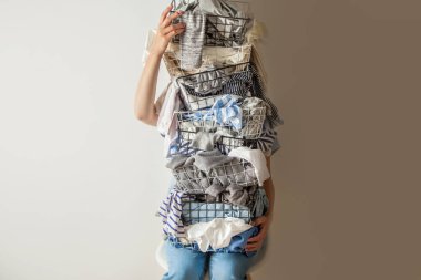 Beyaz arka planda dağınık giysileri olan metal çamaşır sepetini tutan sürpriz bir kadın. Çamaşır. İzole edilmiş ev hanımı. Uzayı kopyala Tekstil. Kirli gardırop. Dekluting konsepti. Düzensiz eş.