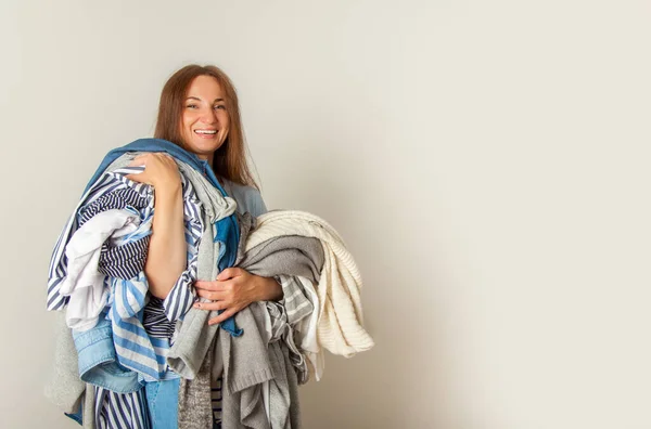 Mujer Joven Feliz Sosteniendo Montón Ropa Desordenada Temporada Sobre Fondo —  Fotos de Stock