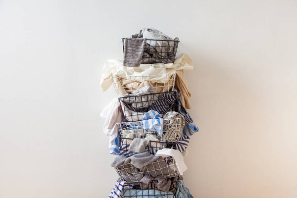 One row of stacked metal laundry basket with full of clothing on white background. Nobody. Copy space. Textile. Mixed dirty wardrobe. Decluttering concept. White background.