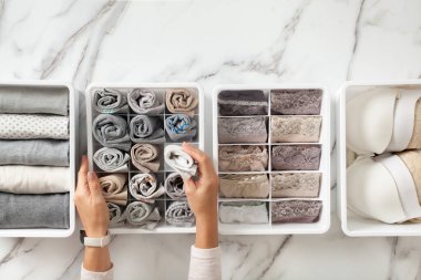 Kadın elleri katlanmış iç çamaşırlarıyla gardırop düzenleyicilerini yerleştiriyor. Katlanmış çoraplı çorap çekmecesi. Mükemmel ve düzgün bir kıyafet. Keten çekmece düzenleme çözümü. Mükemmeliyetçi..