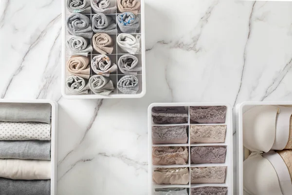 Kadın iç çamaşırı, pijama ve çorapları düzgünce katlanmış ve beyaz mermer masanın üstündeki dolap düzenleyici çekmeceye yerleştirilmiş. İç çamaşırlarıyla dolu bir gardırop. Organize iç çamaşırı çekmecesini muhafaza etmek.