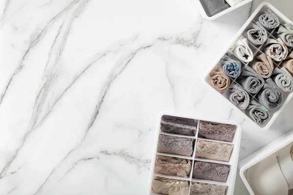 Tertipli ve düzenli katlanmış iç çamaşırları beyaz mermer arka planda düzenleyici çekmece bölmesinde. İç çamaşırlarının dökülmesi. Düzenli yer ve çekmece deposu. Kopyalama alanı.