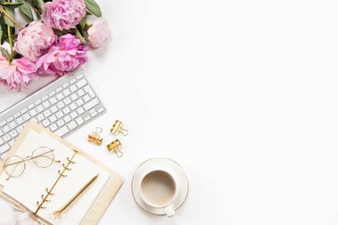 Ofis masasının klavyeli aksesuarları altın tepside kahve ve beyaz arka planda bitki. Evrak işleri için temiz çarşaflı günlük, altın kalem ve kağıt makası. Boşluğu kopyala