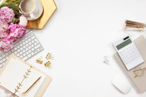 Ofis masasının klavyeli aksesuarları altın tepside kahve ve beyaz arka planda bitki. Evrak işleri için temiz çarşaflı günlük, altın kalem ve kağıt makası. Boşluğu kopyala
