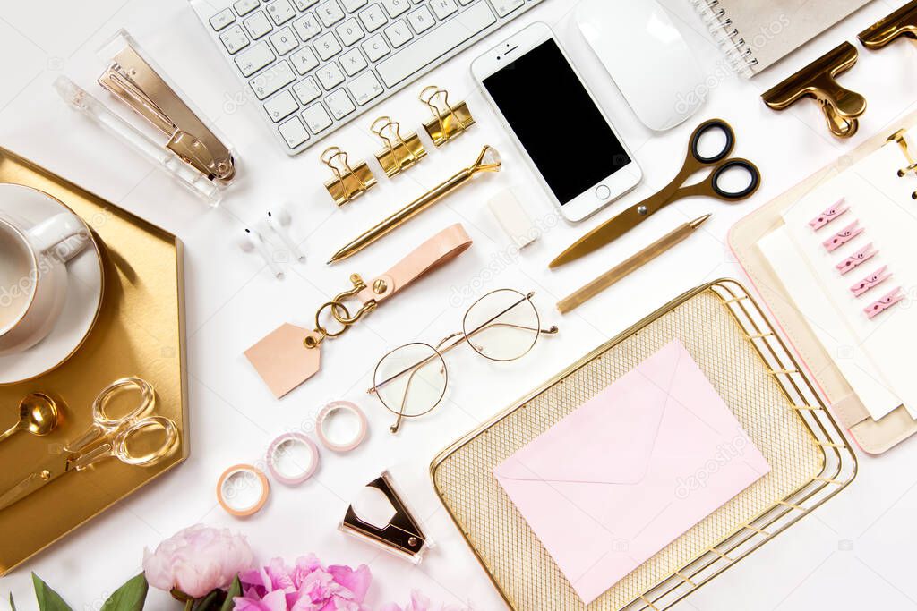 Neatly arranged office stationery with modern gadgets, devices, coffee and flowers on white desk. Top view of school or office supplies. Envelope with useful copy space ready for text or logo.