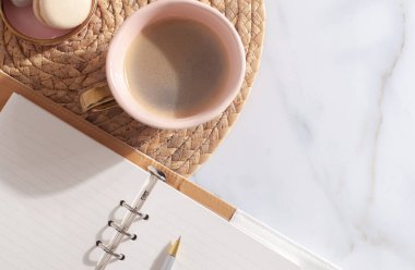 2021 yılı için pembe mercan renkli günlük, kalem, kahve latte, badem kurabiyesi ve beyaz mermer arka planda saman işlemeli plasemat. Yeni yıl planlama konsepti. Minimalist çalışma istasyonu. Boşluğu kopyala.