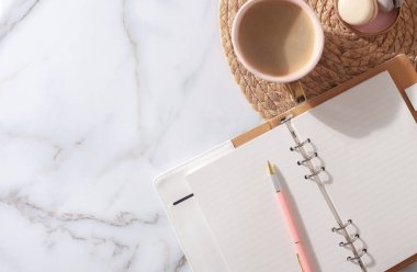 2021 yılı için pembe mercan renkli günlük, kalem, kahve latte, badem kurabiyesi ve beyaz mermer arka planda saman işlemeli plasemat. Yeni yıl planlama konsepti. Minimalist çalışma istasyonu. Boşluğu kopyala.