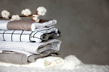 Farklı dizayn modelleri olan katlanmış sıcak battaniye yığını ve gri arka planda pamuk dalı. Örgü battaniyeler. Doğal bitki bazlı tekstil lifleri üretimi. Üretim. Organik ürün