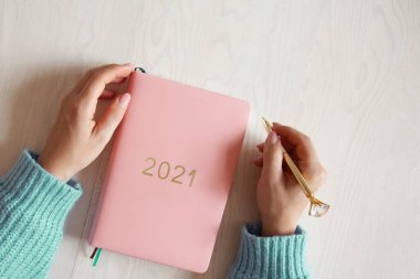 Masada mercan renkli 2021 günlük kitabı olan sıcak süveter giyen kadın resmi var. 2021 yılının gelecek planları ve başarıları. Refah yaşam tarzı
