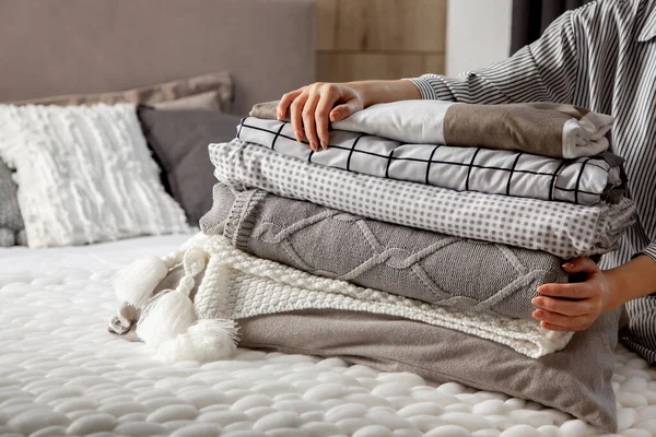 Kışın kalın ve kalın bornozlu güzel bir kadın oturmuş çarşafları düzgünce katlıyor ve beyaz banyo havluları kullanıyor. Temiz çamaşırları düzenlemek ve sıralamak. Organik ve doğal pamuk tekstili. Üretim.