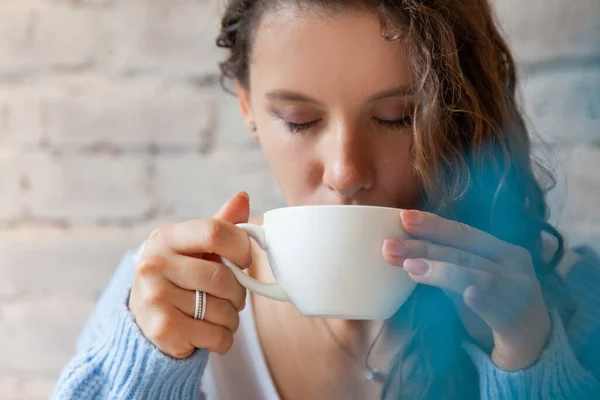 快乐的年轻女人 穿着针织的暖和毛衣 手牵着一杯健康的热蓝色咖啡拿铁 蓝色咖啡拿铁 用新鲜咖啡豆和蓝海蝴蝶茶制成 福利概念 — 图库照片