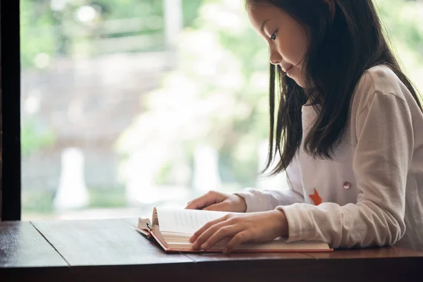 かわいい女の子は笑顔で図書館の本を読んで座って 子供の概念 教育概念 — ストック写真