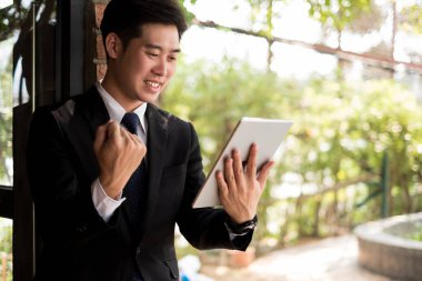 İş adamı gülümseyerek kollarını kaldırarak başarıyı kutluyor ofiste çalışıyor, iş konsepti, başarı konsepti