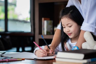 Sevimli kız gülümsedi ve kütüphanede bir kitap çizmeye başladı. Çocuk konsepti, eğitim konsepti.