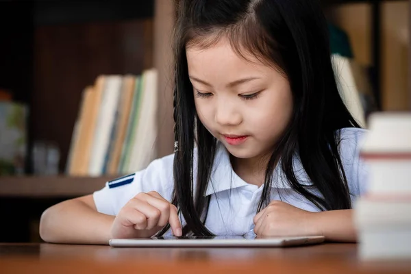 かわいい女の子の笑顔座って 図書館でラップトップコンピュータをプレイ 子供の概念 教育の概念 — ストック写真