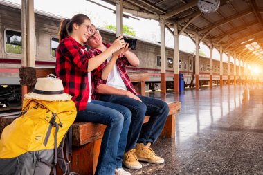 Birlikte gezen mutlu genç çiftler tren istasyonunda fotoğraf çekiyorlar, seyahat konsepti, çift konsepti. 