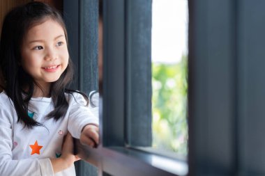 Ayakta duran tatlı kız gülümsedi. Odaya bak, çocuk konsepti, eğitim konsepti.