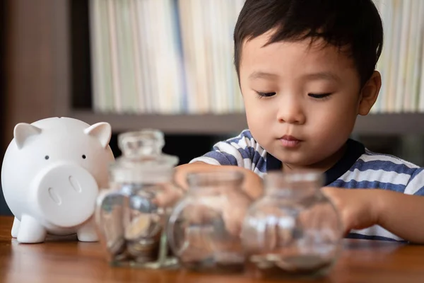 可爱的男孩把钱币存进储蓄罐 存钱的概念 — 图库照片