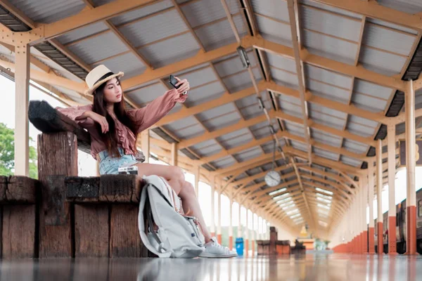 Улыбающаяся женщина путешественник с рюкзаком держа смартфон на holid — стоковое фото