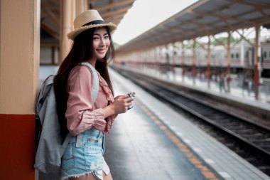 Sırt çantalı gülümseyen kadın gezgin elinde antika kamerayla...