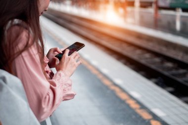 Sırt çantalı, gülümseyen kadın gezgin. Elinde akıllı telefon var.