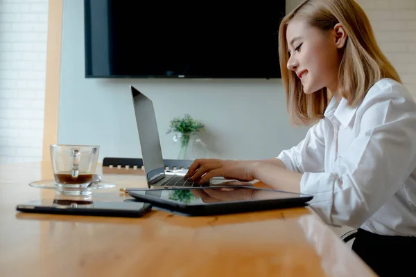 Junge Geschäftsfrau arbeitet mit Mobiltelefonen und Notebooks in der — Stockfoto