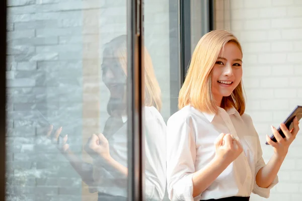 Jonge zakenvrouw staande in de buurt van het kantoor venster lachende armen — Stockfoto