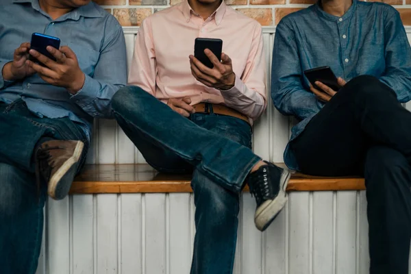 Genç iş adamları ahşap masa üzerinde akıllı telefon kullanıyor. — Stok fotoğraf