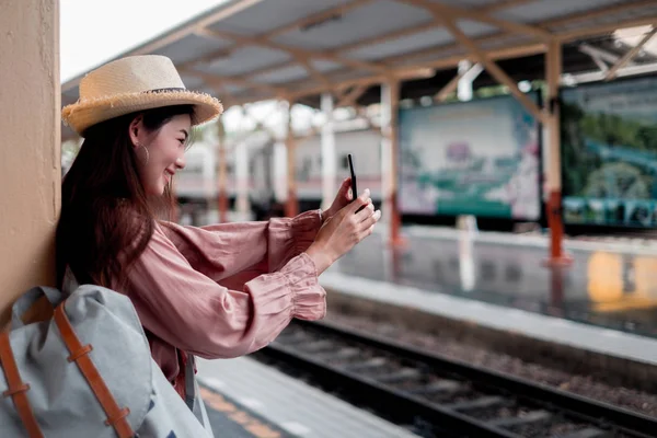 Mujer sonriente viajero con mochila sosteniendo smartphone en holid — Foto de Stock