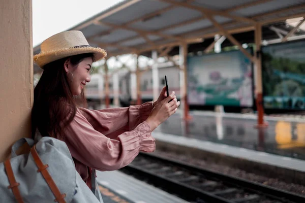 Smiling woman traveler with backpack holding smartphone on holid — Stock Photo, Image